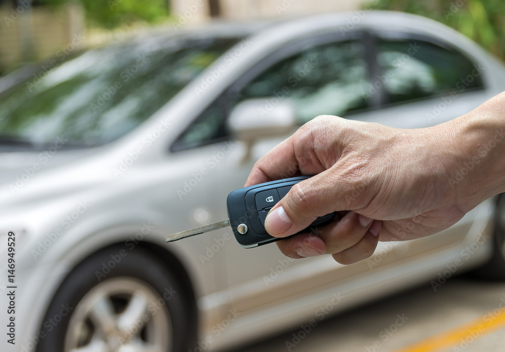 Hand holding the keys over photo blurred of used car for open the door car, transportation and ownership concept Hand holding the keys over photo blurred of used car for open the door car, transportation and ownership concept