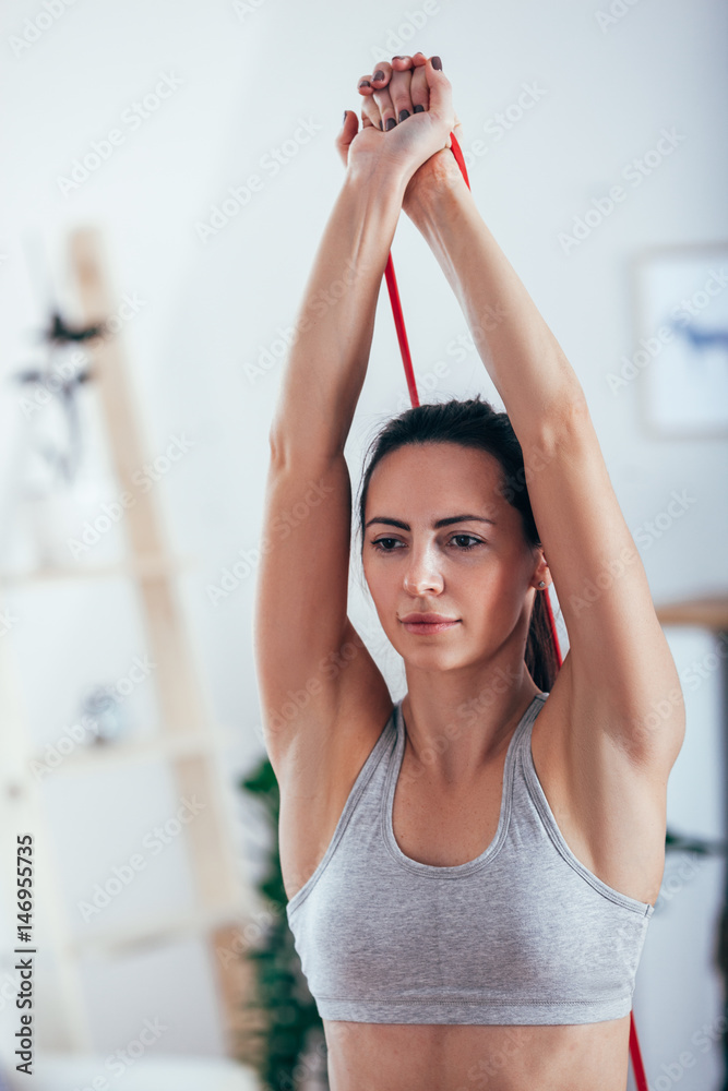 Sporty athletic woman exercising with rubber tape