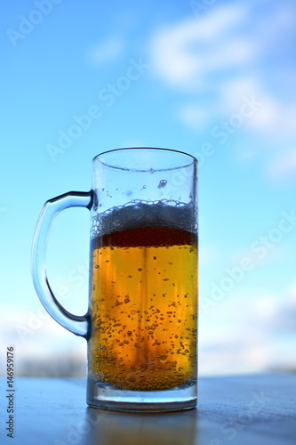 mug of light beer with foam and bubbles on sky background