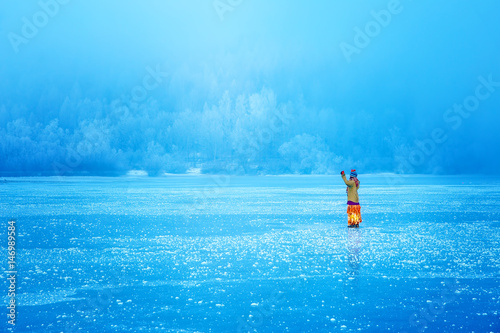 Woman on ice lake in beautiful ethno dress. Prayer for the lake.