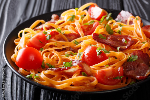 Foto Carrot pasta with fried bacon, greens and tomatoes close-up on the table
