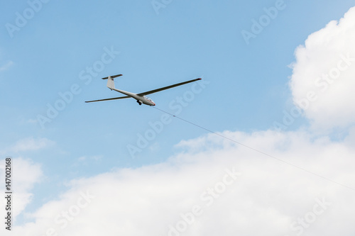 Glider towed on a rope flying on a blue sky background. © murmakova
