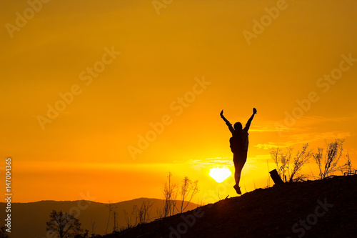 Woman backpacking to watch the sunset.Silhouette Jumping glad