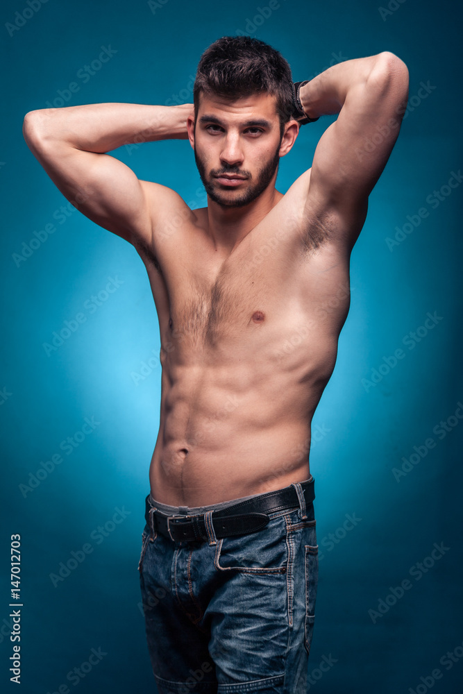 one young adult man, shirtless body, arms raised one young adult man, shirtless body, arms raised