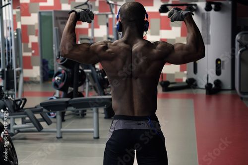Athlete muscular bodybuilder posing in the gym.
