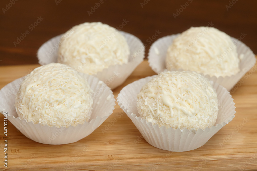 White chocolate candies with coconut topping on wooden background