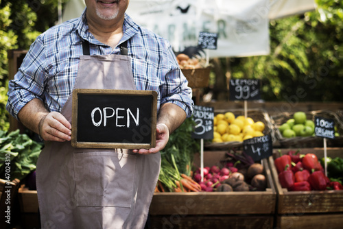 Greengrocer selling organic fresh agricultural product at farmer market photo