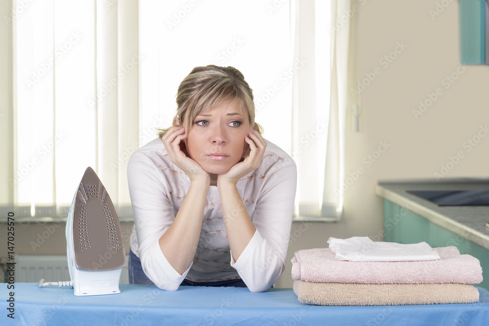 Lazy up housewife sitting amongst her clean laundry piled on the ironing board daydreaming Lazy up housewife sitting amongst her clean laundry piled on the ironing board daydreaming