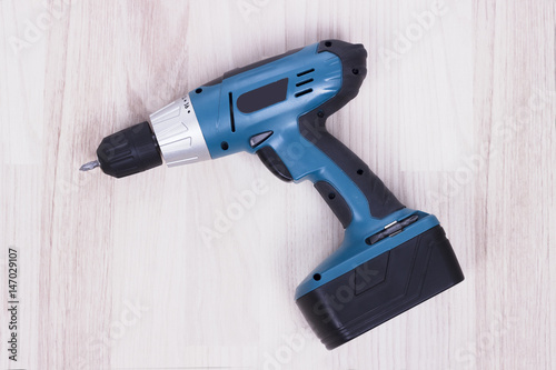 Battery screwdriver or drill isolated over wooden background