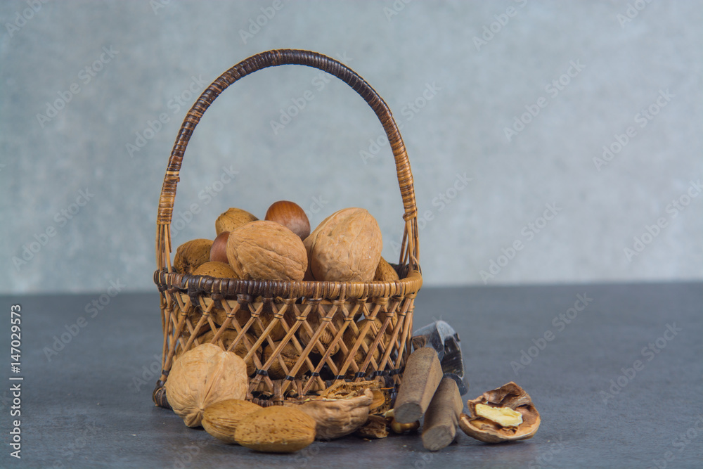 Nuts mix in shell - walnuts, hazel and almonds with nut chaker on grey concrete backgrund Nuts mix in shell - walnuts, hazel and almonds with nut chaker on grey concrete backgrund