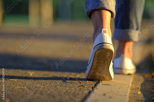 Sneaker and jeans walking on the road with beautiful sunset