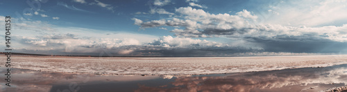 Scenery panorama of frozen sea during ice drift on springtime with dramatic sky and clouds having reflections in melt water on evening in Novosibirsk, Russia