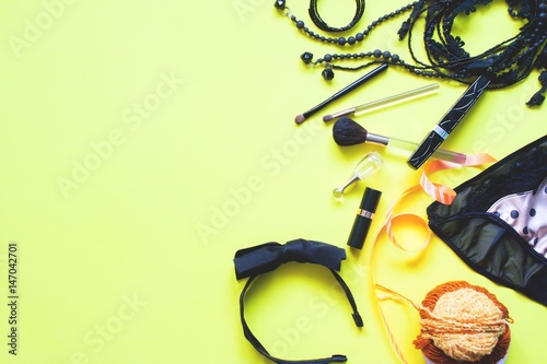 Flat lay of female asccessories in black and golden concept on yellow background, Spring fashion concept with copy space