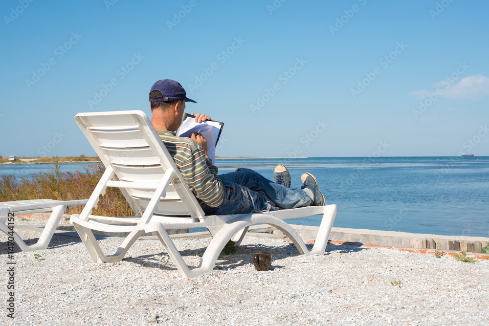 Man is sitting on a deckchair by the sea, developing the project
