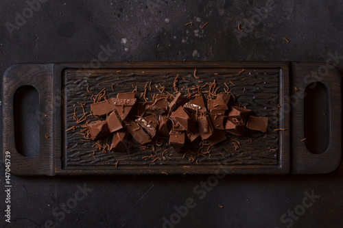 Milk chocolate. Milk chocolate pieces on a wooden background photo