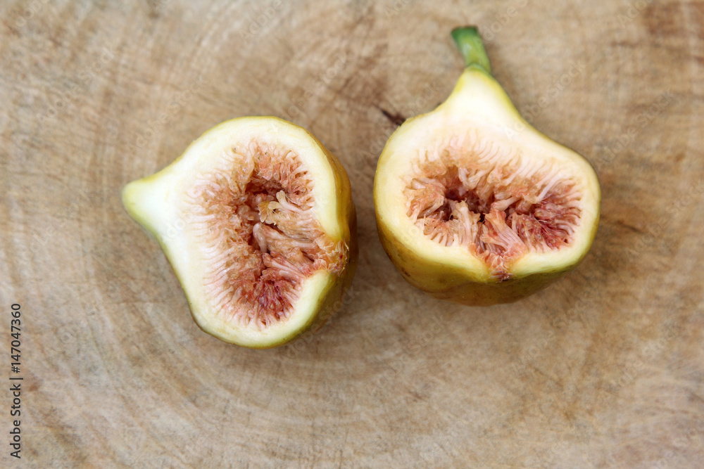 Common fig fruits cut open showing the flesh on wooden background, Top view.