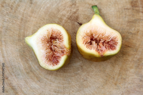Common fig fruits cut open showing the flesh on wooden background, Top view. photo