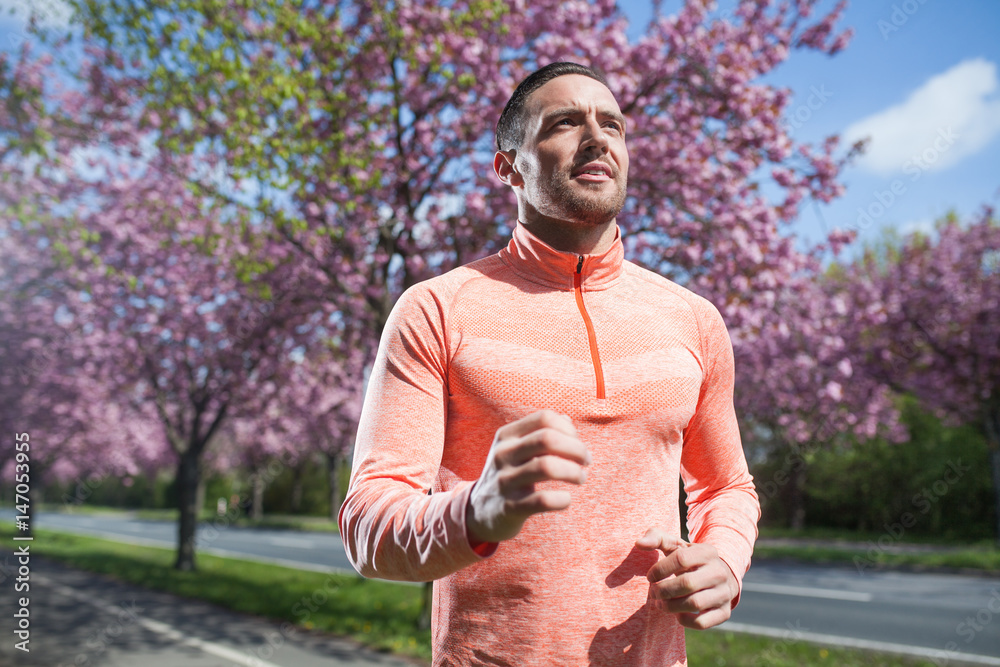 Fototapeta premium Joggender Mann im Park im Frühling im Sonnenschein