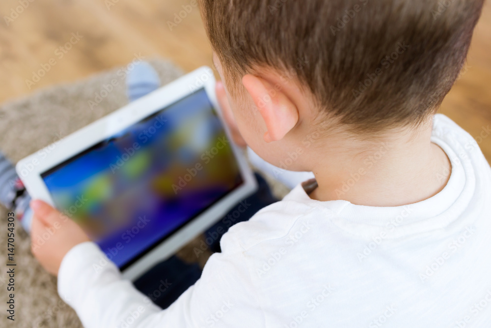 Beautiful young boy using his digital tablet at home. Beautiful young boy using his digital tablet at home.