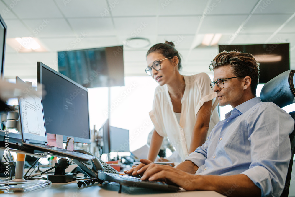 Mature businessman working on computer with colleague Mature businessman working on computer with colleague