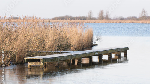 Wooden jetty at lake at cold winter day