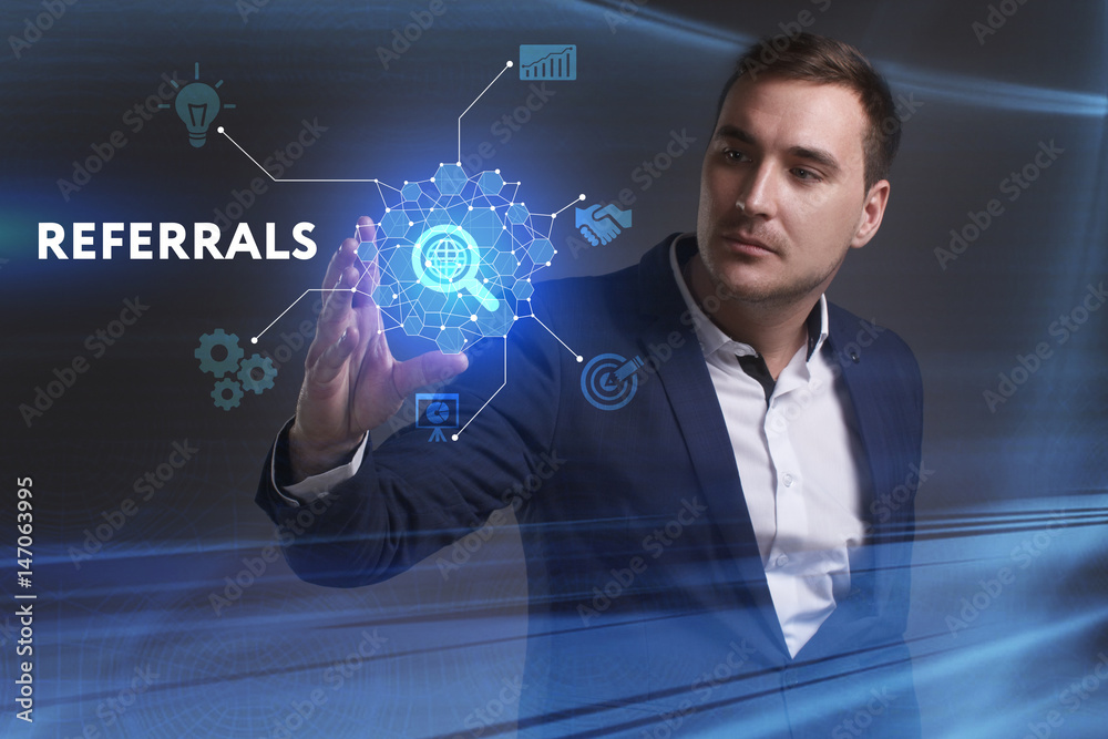 Business, Technology, Internet and network concept. Young businessman working on a virtual screen of the future and sees the inscription: Referrals Business, Technology, Internet and network concept. Young businessman working on a virtual screen of the future and sees the inscription: Referrals
