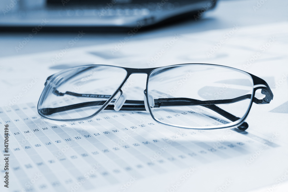 Eyeglasses on a business document, blue toned Eyeglasses on a business document, blue toned