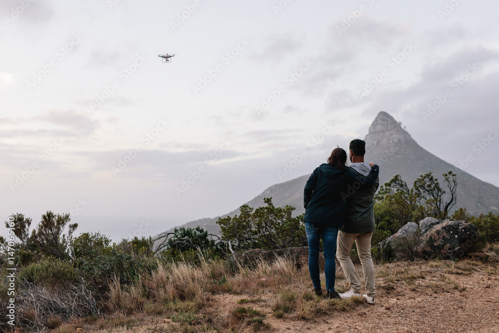 Young couple flying drone in countryside