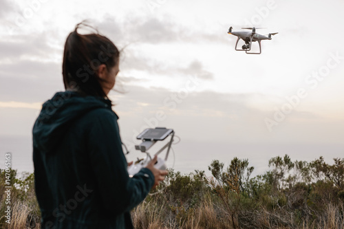 Woman watching and navigating a flying drone