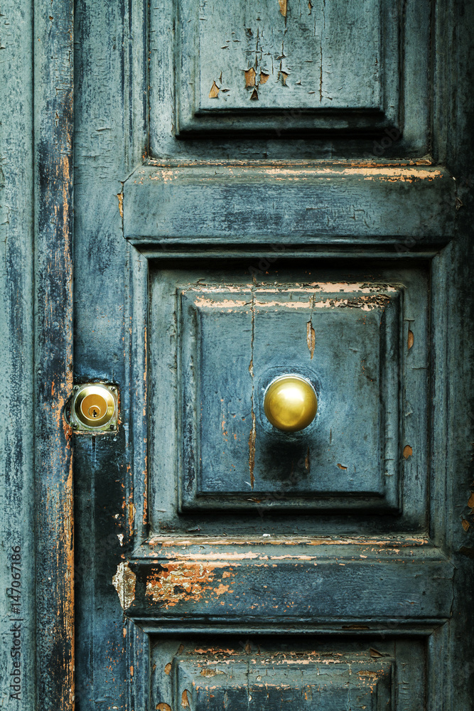 Closeup of blue turquoise old textured antique door with gold bronze door handle and keyhole. Vertical.
