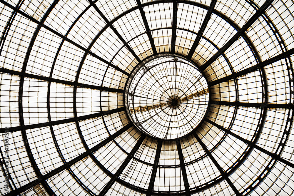 Closeup of a glass roof with metal frame circle and lines. Indoors. Daylight. Background glass graphic architecture elements. Milan, Italy.