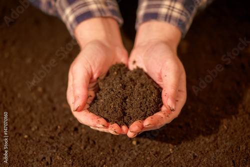 Handful of arable soil in hands of responsible farmer