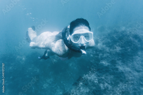 Girl snorkeling in deep blue sea.