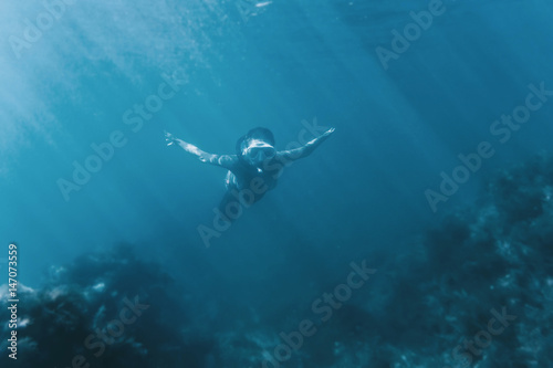 Female free diver swimming underwater.