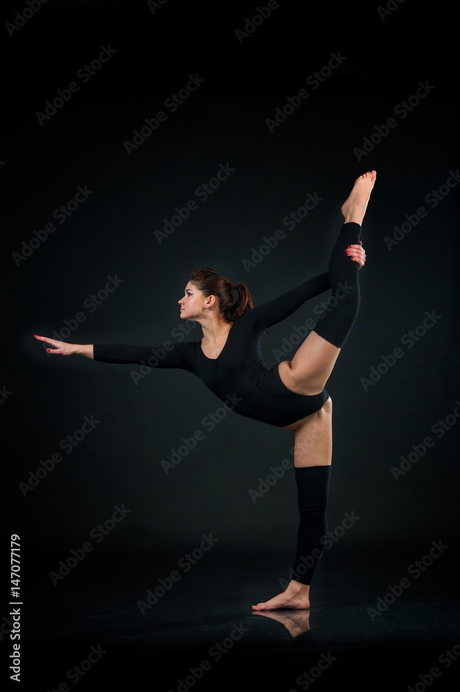 Sporty gymnastics woman stretching on One leg on black background Sporty gymnastics woman stretching on One leg on black background
