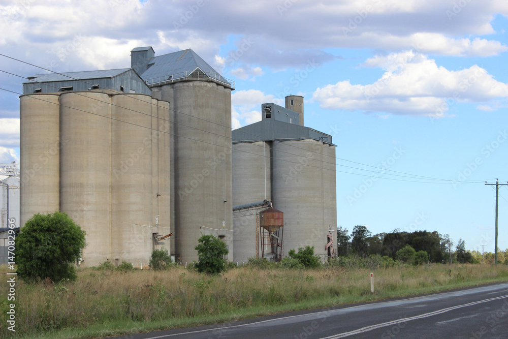 Grain silos from highway and cloudy sky