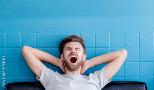man yawning and going asleep in his living room