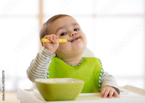 Happy baby boy spoon eats itself