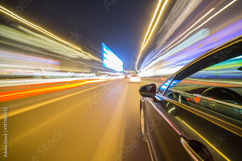 View from Side of Car moving in a night city, Blured road with lights with car on high speed. Concept rapid rhythm of a modern city.