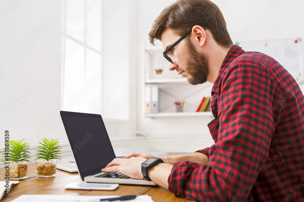 Young businessman working with laptop in modern white office Young businessman working with laptop in modern white office