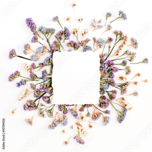 Fototapeta Naklejka Na Ścianę i Meble -  Empty white paper blank on blue and purple dried flowers frame on white background. Flat lay, top view
