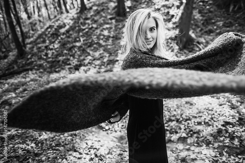 Pretty blonde whirls her coat standing in the forest