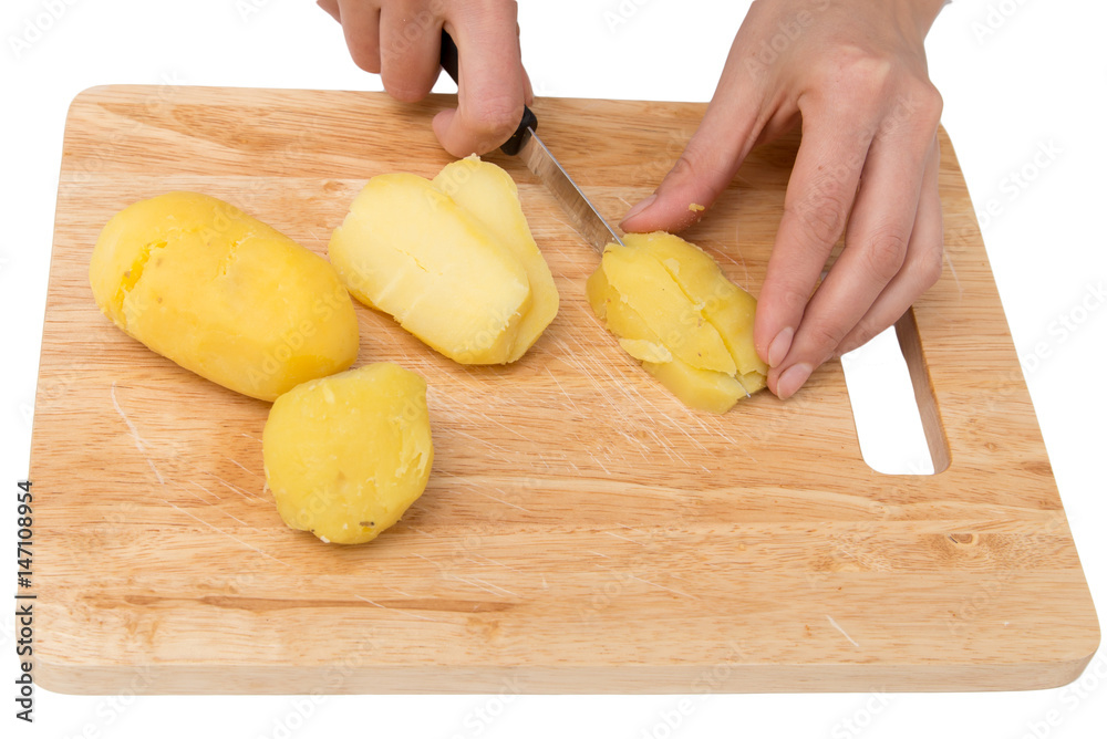 Chef cuts boiled potatoes on board on a white background Chef cuts boiled potatoes on board on a white background