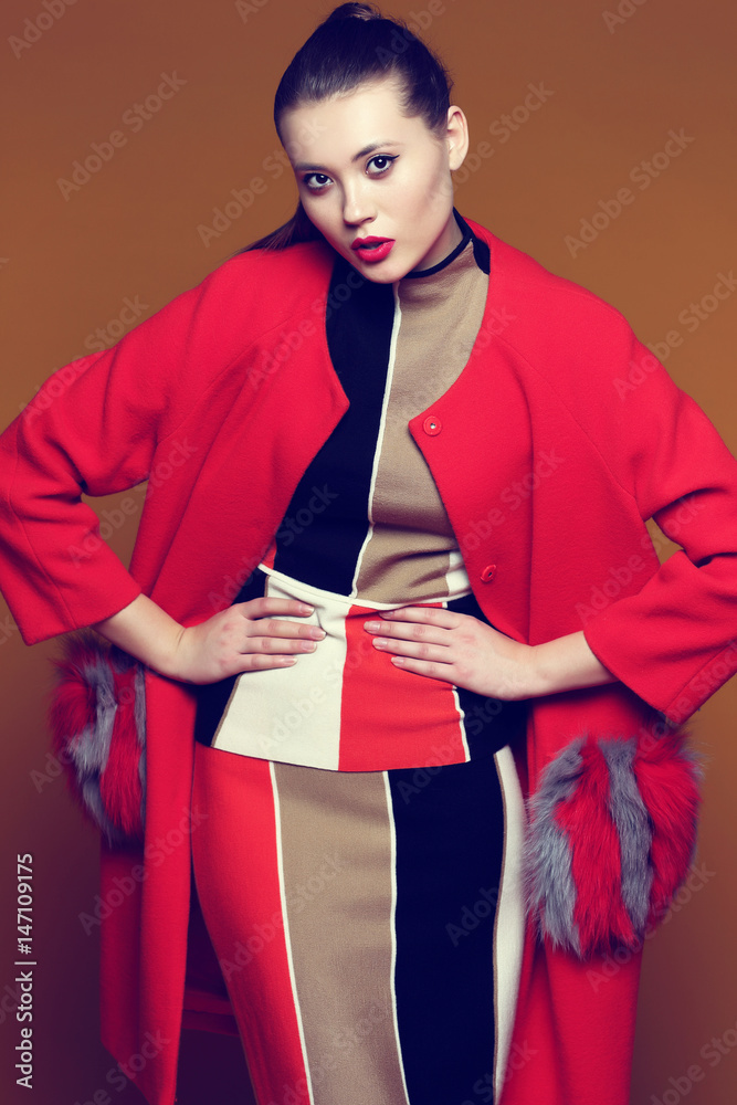 Fashion portrait of young asian woman in trendy skirt, top and red coat.