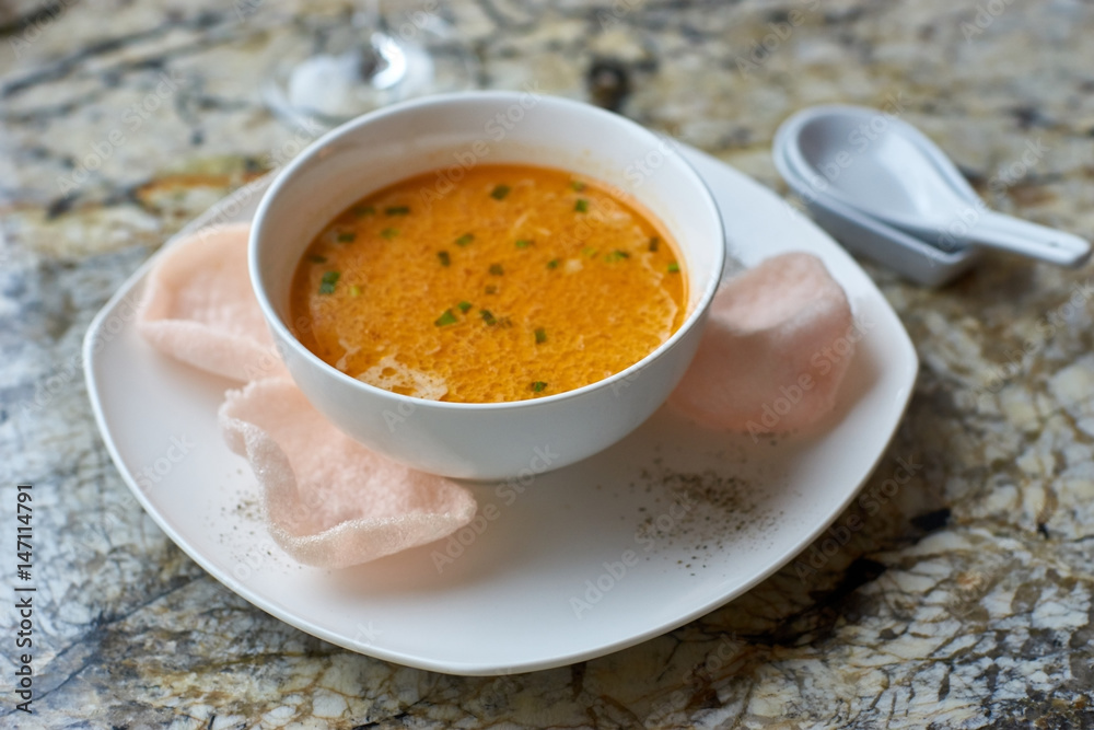 Creamy crab soup served with crab chips and glass of white wine on marble backround