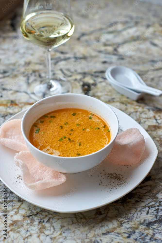 Creamy crab soup served with crab chips and glass of white wine on marble backround Creamy crab soup served with crab chips and glass of white wine on marble backround