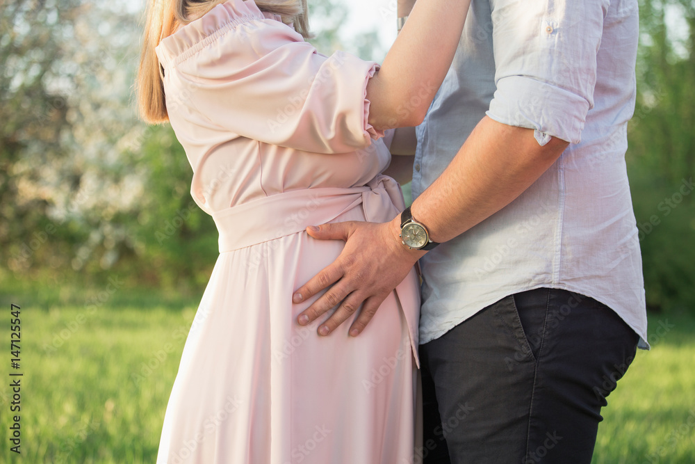 Young parents in a spring park at sunset. Pregnant woman. Young parents in a spring park at sunset. Pregnant woman.