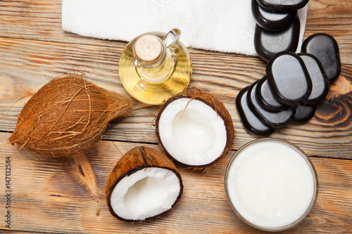 Oil, coconut and stones for a massage on wooden background
