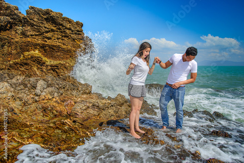 A mixed race couple - Thai man and European woman - at a cliff, watching waves making splashes