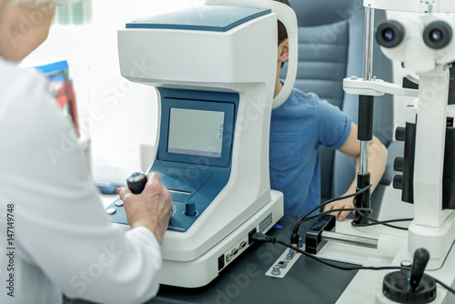 Female oculist checking sight by apparatus photo